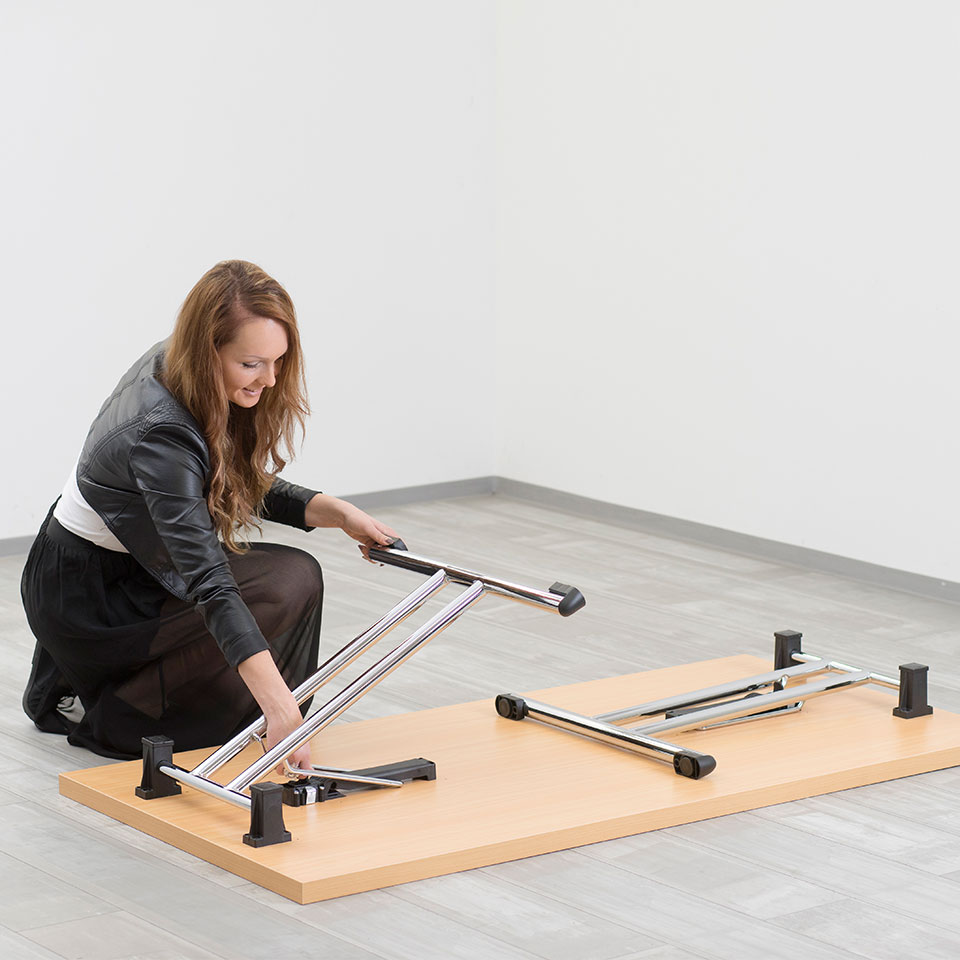 Klapptisch fürs Büro als Klappschreibtisch stapelbar in buche / einfach Aufklappen Aufbau mit Hintergrund